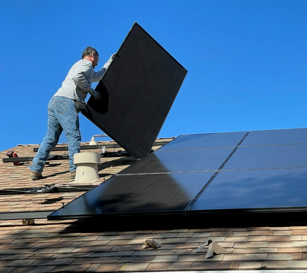 man in white dress shirt and blue denim jeans sitting on white and black solar panel